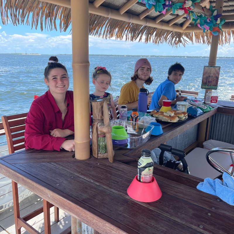 Young group eating and chilling on a bout with Charleston Tiki Boat